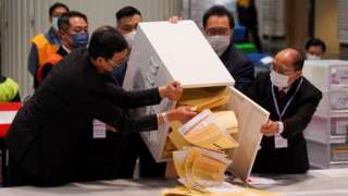 The chairman of Electoral Affairs Commission Barnabas Fung Wah and other members of EAC open the ballot box for the Legislative Council election at a vote counting centre, in Hong Kong, China 19 December 2021