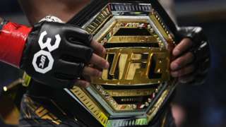 A fighter holds a UFC belt around his waist
