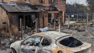 Wrecked house and car after wildfire spread to buildings
