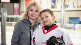 Kateryna and Kateryna smile while standing in front of an ice rink