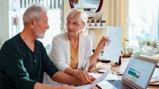 newspaper article on business Pensioner couple - stock image