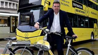 Andy Burnham poses with bike, bus and tram