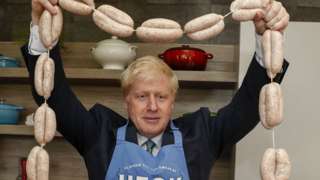 Boris Johnson holding a string of sausages