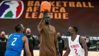 Basketball Africa League president Amadou Gallo Fall (centre) with the ceremonial tip off of the first game of the competition between Nigeria's Rivers Hoopers and Rwanda's Patriots