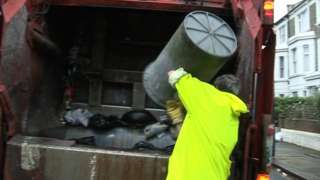 Binman tips rubbish bin and deposits refuse into back of refuse truck in Hammersmith