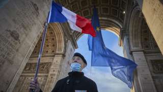 A veteran stands with the French flag next to a giant flag of the European Union at the Arc de Triomphe on January 01, 2022 in Paris, France.