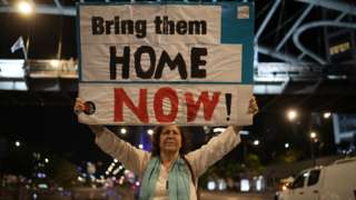A woman holds a sign in Tel Aviv, Israel demanding the hostages are brought home