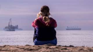 Young woman looks out onto an oil rig