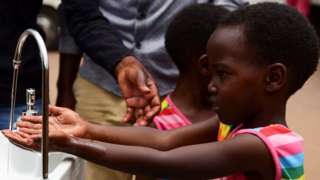 طفلة تغسل يديها باستخدام صنبور بأحد شوارع كيغالي، عاصمة رواندا