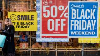 Woman stands near Black Friday sale signs