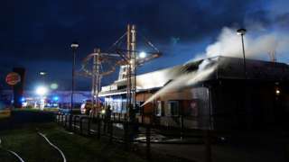 Fire crews tackle a fire at a Burger King in Bedford while smoke is seen coming from its roof.
