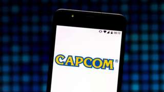 The Capcom logo is seen on a smartphone screen against a textured pixel background
