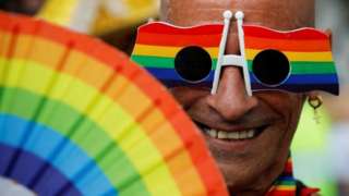 Person with rainbow fan and glasses
