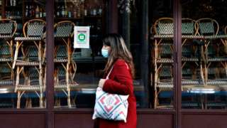 A woman walks past a closed restaurant in Paris on 18 November