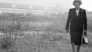 Margaret Thatcher walking through a derelict site