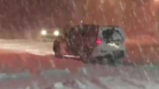 An SUV struggles to drive along a snow covered road in Portland, Maine