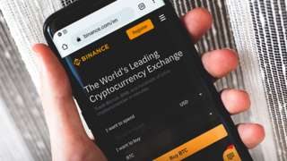 Binance cryptocurrency exchange website interface on a smartphone held in hand