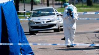 A forensics officer takes photographs at the scene on College Road, Kingstanding, north of Birmingham