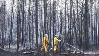 Annapolis Royal firefighters Jason Rock and Anthony Lopiandowski spray hot spots in the Birchtown area, while tackling wildfires in Shelburne County, Nova Scotia, Canada June 3, 2023.