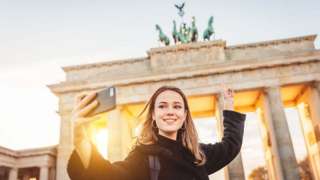 Tourist taking selfie at Brandenberg Gate in Berlin