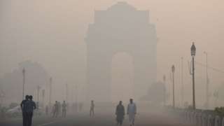 Indian pedestrians walking near the India Gate monument amid heavy smog in New Delhi on October 20, 2017