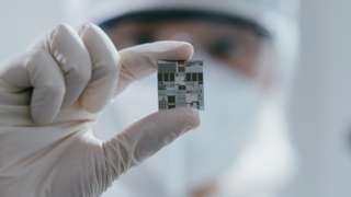 newspaper article on business A female engineer inspects a wafer chip.