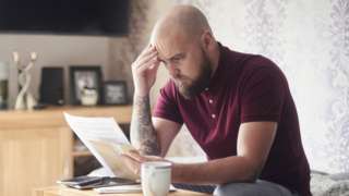 A stock photo of a man looking worriedly at his energy bills