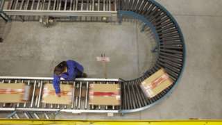 A worker scanning boxes on a conveyor belt
