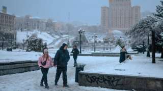 People walk through a snowy scene in Kyiv