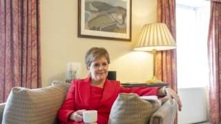 Nicola Sturgeon sits on a sofa with a cup of tea in Bute House