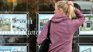A woman looks at an estate agent window