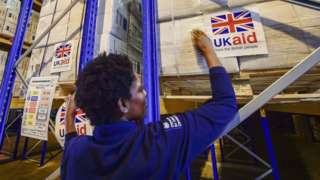File photo dated August 2014 of logistics officer placing UK Aid stickers onto cargo pallets containing British aid items destined for areas suffering humanitarian crisis