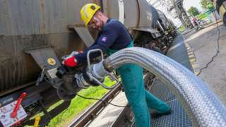 A worker prepares to receive liquid additive for petroleum refining from a tanker train at the Duna (Danube) Refinery of Hungarian MOL Company located near the town of Szazhalombatta