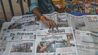 A newspaper vendor arranges newspapers displaying front page news about Afghanistan in Siliguri on 17 August, 2021