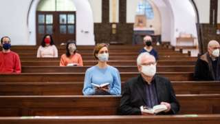 People wearing masks socially distance in a church