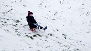 A child rides a toboggan down a hill after heavy snow fall in Balboa, in Co Carlow