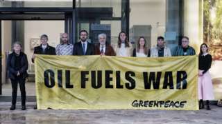 Greenpeace activists with banner that reads foil fuels war
