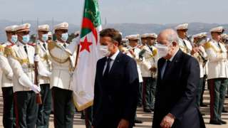 French President Emmanuel Macron (L) and Algeria's President Abdelmadjid Tebboune review a guard of hounour at the airport in Algiers on August 25, 2022, at the start of an official visit to Algeria.