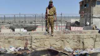 A Taliban fighter stands at the scene of the attack