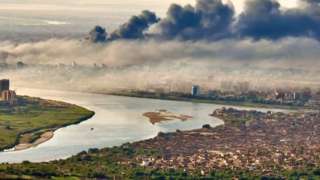 An aerial view of black smoke covering the sky above the Sudanese capital Khartoum