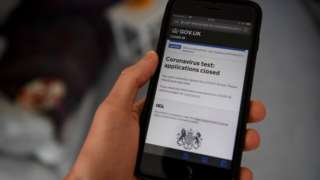 A mobile phone shows the government's coronavirus test application website