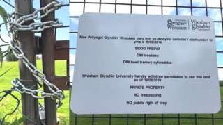 Locked gate and sign at Glwyndwr University owned field in Rhosnesni