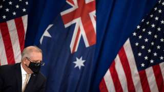 A masked Scott Morrison in front of the Australian and American flags