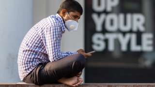 A man wearing a facemask as a preventive measure against the Covid-19 coronavirus checks his mobile phone in New Delhi on November 20, 2020.