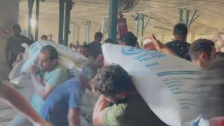 Displaced Palestinians carry food bags and boxes as they storm an UNRWA food supply centre in Deir el-Balah in the southern Gaza Strip after smashing doors on 28 October