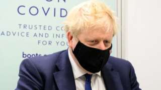 Britain's Prime Minister Boris Johnson prepares to watch a man receive his Covid-19 booster jab, 10 January 2022