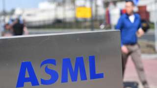 An employee walks past an ASML logo