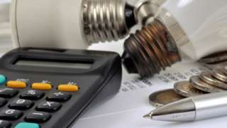 Light bulbs, calculator, money, pen and energy bill