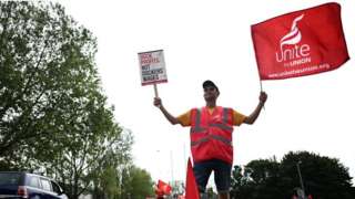 A dock worker waves a flag of the trade union "Unite the Union" during a strike at a port in Suffolk