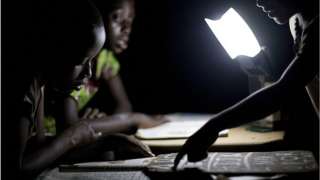Ghanian students study at night using smart LED lanterns provided by Empower Playgrounds.
